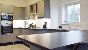 A modern kitchen with built-in appliances, a large island, and a window providing natural light. - 2 bedroom accommodation in Glandwr, near Narbeth (Glandwr, near Narbeth)