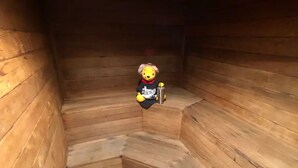 A wooden interior with a bear figure holding a cup.