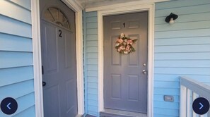 A house with a front door marked with the number 1, a porch with a railing, and a wreath on the door.