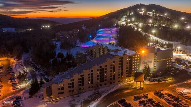 A hotel with multiple buildings, a parking lot, and a ski slope with illuminated areas. - SLOPES VIEW, SKI IN AND OUT AT SILVER CREEK, SLEEPS 4. (Snowshoe)