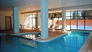 An indoor swimming pool with clear blue water, surrounded by lounge chairs and large windows offering a view of the outside. - SLOPES VIEW, SKI IN AND OUT AT SILVER CREEK, SLEEPS 4. (Snowshoe)