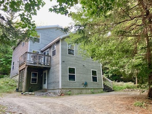 A two-story house with a balcony, a front porch, and a staircase leading to the upper level. - Nestled between Bar Harbor and Acadia, a bright and spacious house in the woods (Bar Harbor)