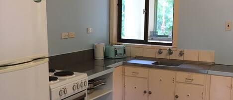 Una pequeña cocina con refrigerador, estufa, horno y una ventana con vistas.