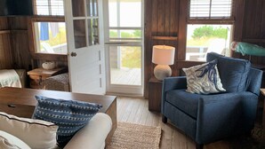 Una camera accogliente con arredamento in legno, una poltrona blu, una porta bianca e vista sull'esterno.