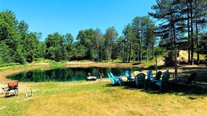 Ein Campingplatz am Seeufer mit einem Boot, Stühlen und einem Zelt.