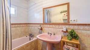 A bathroom with a bathtub, a sink, a mirror, and a shower curtain.