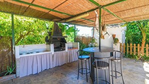 An outdoor kitchen area with a grill, bar stools, and a table.