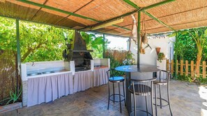 An outdoor kitchen area with a grill, bar stools, and a table.