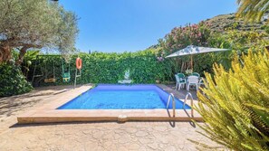 A rectangular swimming pool with a clear blue water surface, surrounded by a stone patio.