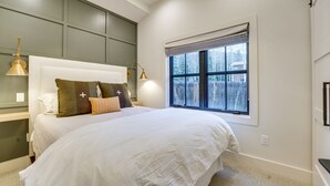 Un dormitorio con una cama grande, una ventana con persianas y dos lámparas de noche.