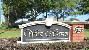 Placa de West Haven com um muro de tijolos e vegetação ao redor.