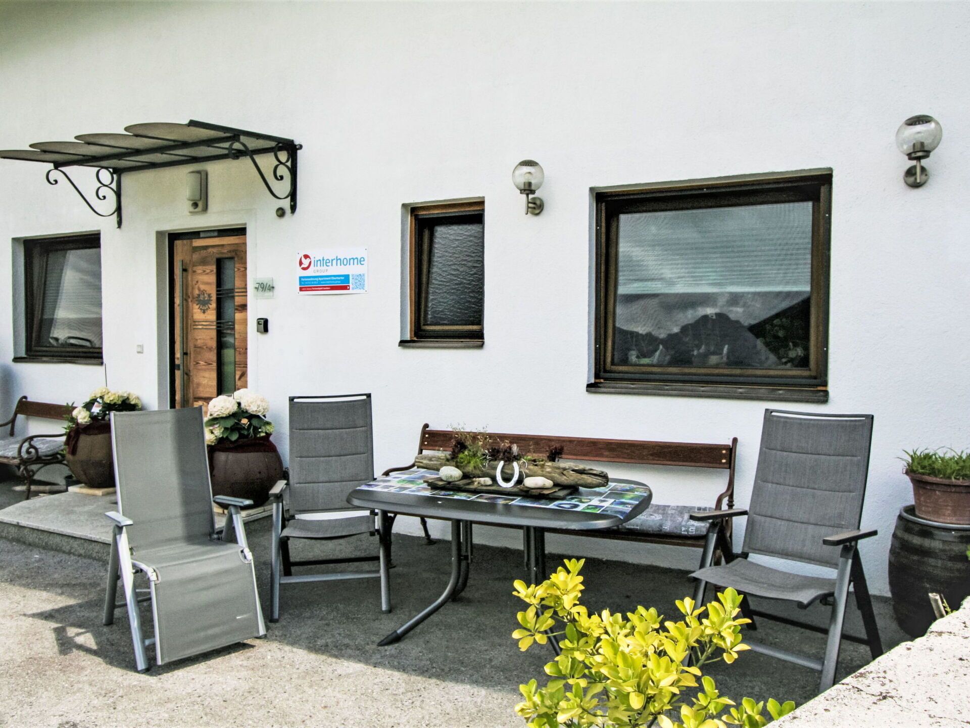 An outdoor seating area with a table and chairs, a wooden bench, and a potted plant.