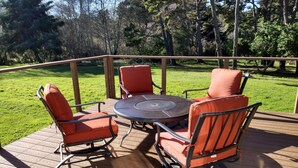Eine Holzterrasse mit einem runden Tisch und vier orangenen Stühlen.