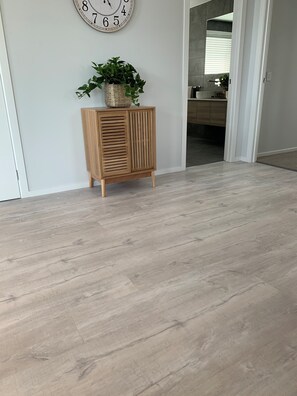 Enter a serene space with a wooden floor, featuring a cabinet and a large wall clock.