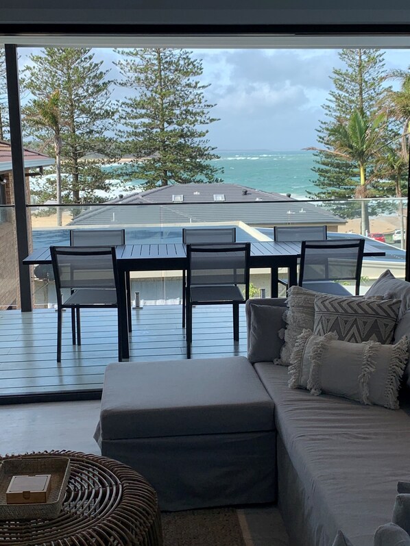 Enjoy ocean views from the spacious living area with a dining table, comfortable sofa, and wicker side table.