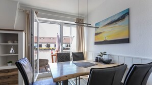 A dining area with a table, chairs, and a view through a glass door. - Bright & Charming Vacation Apartment "Kille - Right Apartment" in Sankt Peter Ording (St. Peter-Ording)
