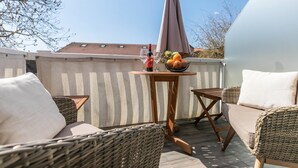 A patio with wicker furniture, a table with a bottle and glasses, and a fruit bowl. - Bright & Charming Vacation Apartment "Kille - Right Apartment" in Sankt Peter Ording (St. Peter-Ording)