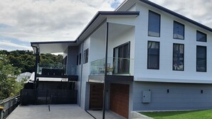 Een modern huis met twee verdiepingen, een overdekt terras, een garage en een keurig onderhouden gazon.