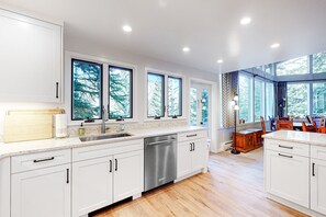 Enjoy meals in this kitchen with white cabinetry, a dishwasher, and a dining table.
