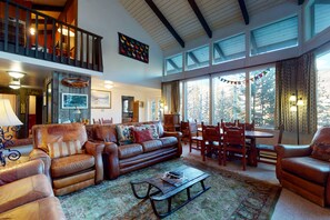 Relax in a spacious living area with a comfortable seating arrangement, dining space, and balcony offering views of the surrounding landscape.