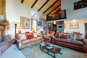 Relax in a spacious living room with a high ceiling, comfortable seating area, and a wooden coffee table.