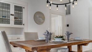 A dining area with a wooden table, two chairs, and a chandelier.