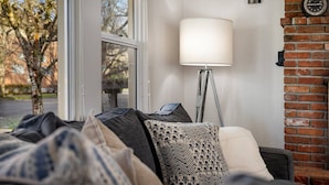 A cozy room with a bed, a lamp, and a brick wall.