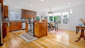 A spacious kitchen with wooden cabinets, a central island, and a dining area with a view of the outdoors.