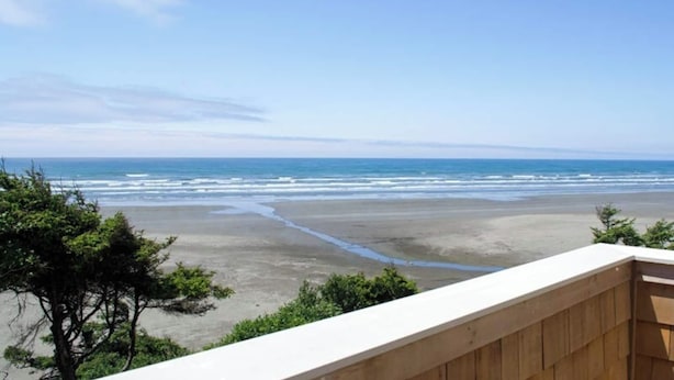 Une vue sur la plage depuis un balcon doté d’une balustrade en bois.