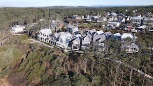 Vue aérienne d’un quartier résidentiel avec des maisons, des routes et une colline boisée.