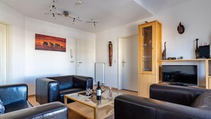 A modern living room with leather sofas, a glass coffee table, a fireplace, and a mounted TV. - Ferienwohnung 7 "auszeit" in der Villa Annabelle (Binz)