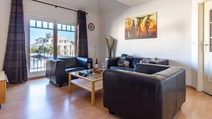 A modern living room with a sofa set, a coffee table, and a large window with curtains. - Ferienwohnung 7 "auszeit" in der Villa Annabelle (Binz)