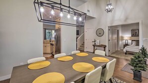 A dining area with a long table, yellow placemats, and a modern chandelier. - Flagstaff Family Getaway ~ 4 Miles to Downtown! (Flagstaff)