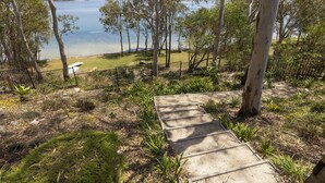 A concrete staircase leading down to a grassy area with a view of a lake and trees.