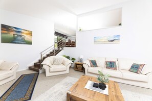 Amplia sala de estar con una escalera, un conjunto de sofás y una mesa de centro.