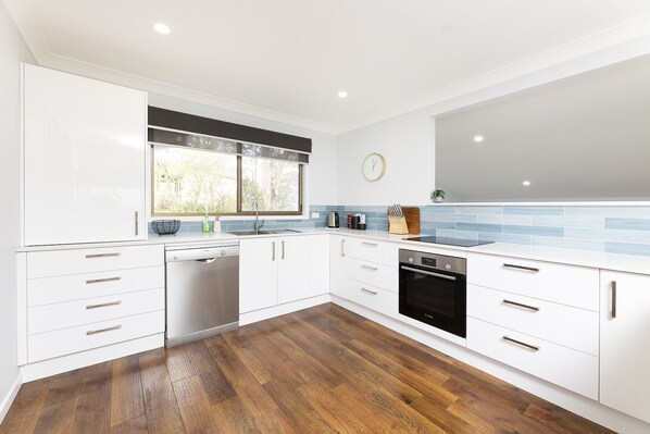Enjoy cooking in this well-lit kitchen with a stainless steel dishwasher and black oven.