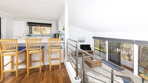 A modern kitchen with a dining area, a living space with a sofa and coffee table, and a balcony with a view.