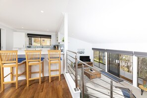 Et moderne køkken med spiseområde, et opholdsområde med sofa og sofabord, samt en balkon med udsigt.
