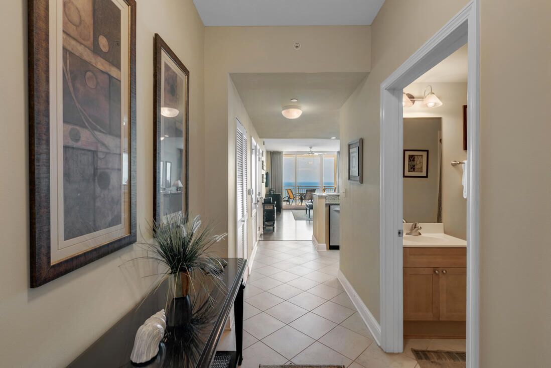 A hallway with a console table, framed artwork, and a view into a dining area.