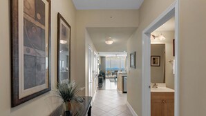 A hallway with a console table, framed artwork, and a view into a dining area.
