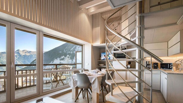 A modern interior with a dining area, kitchen, and a spiral staircase. - Renovated top-floor apartment with slope access, sleeps 6 (Courchevel 1650)