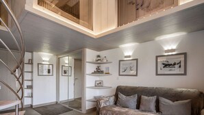 A modern living room with a grey sofa, a glass coffee table, and a spiral staircase. - Renovated top-floor apartment with slope access, sleeps 6 (Courchevel 1650)