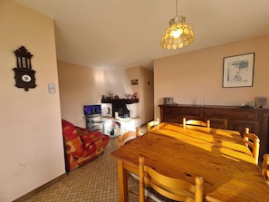 Un comedor con una mesa y sillas de madera, un televisor, una chimenea y un reloj en la pared.