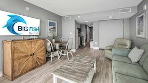 Un salon moderne avec un meuble en bois, un canapé vert et un coin repas comprenant une table et des chaises.