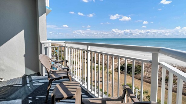 A balcony with a view of the beach and ocean.