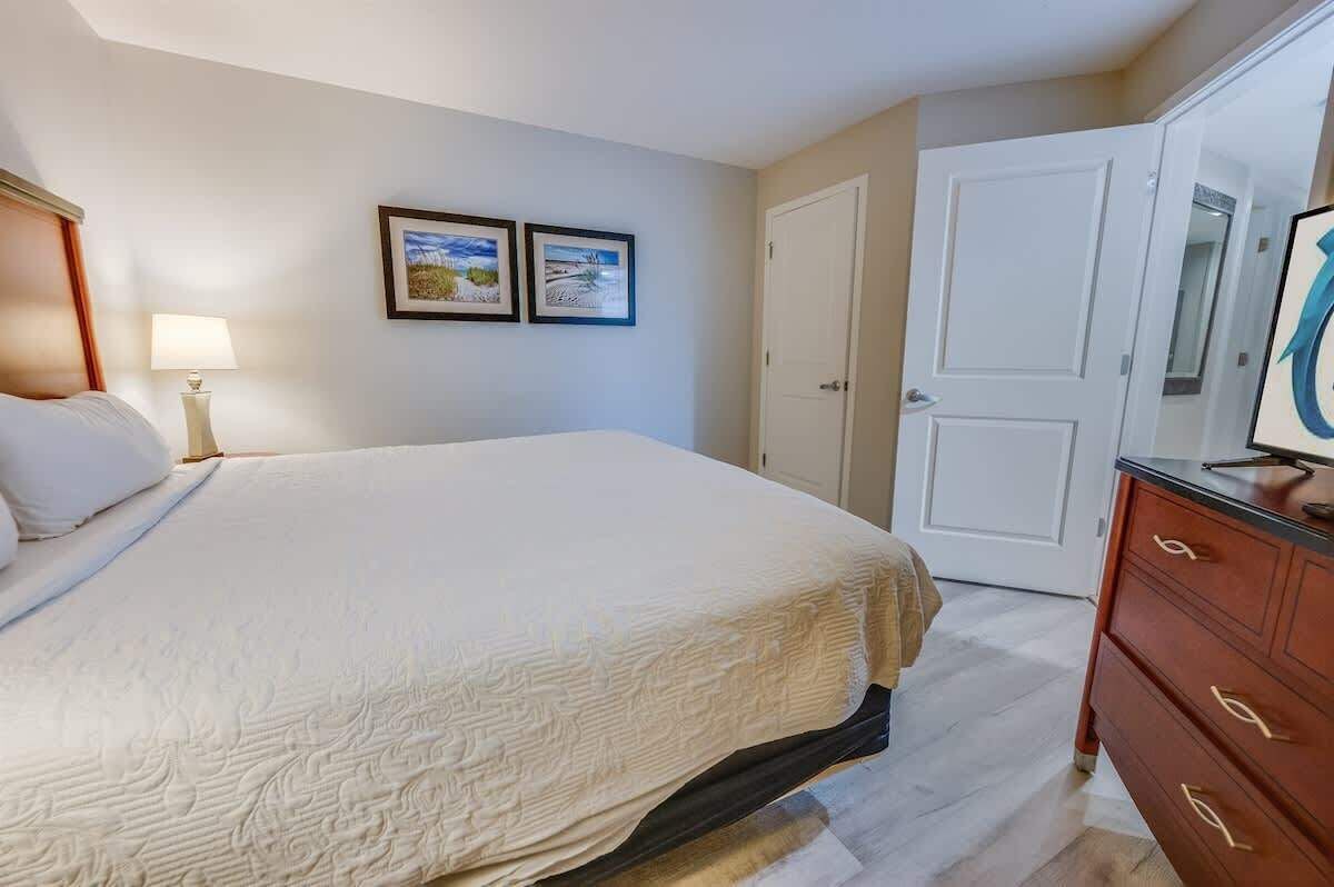 A bedroom with a bed, a dresser, a nightstand, and two framed pictures on the wall.