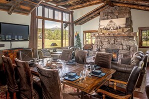 A rustic interior with a stone fireplace, leather seating, and a dining table set for four.