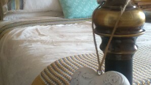 A bed with a white comforter, a blue pillow, and a patterned blanket.