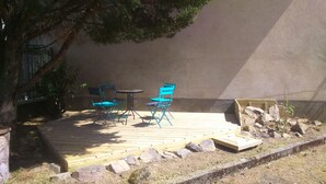 An outdoor patio with two blue folding chairs and a small round table.