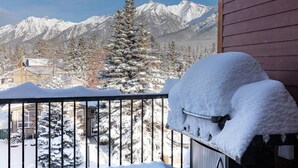 Een balkon met sneeuwbedekte hekken en een barbecue bedekt met sneeuw.